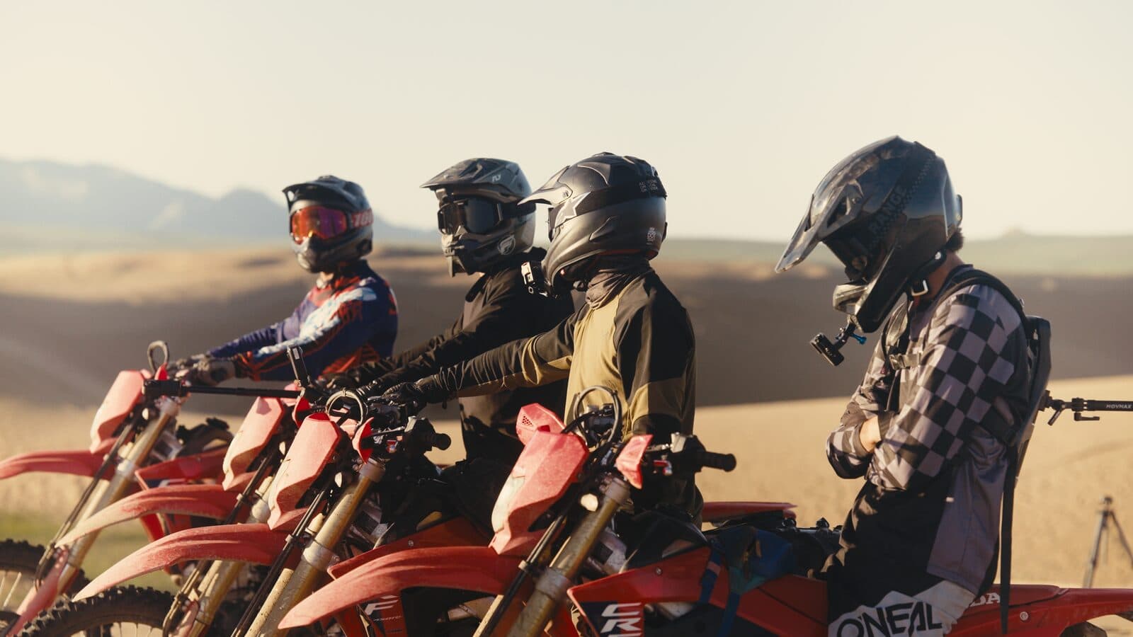 Evolve Moto Tours riders lined up on their Honda CRF450RL motorcycles in the dunes